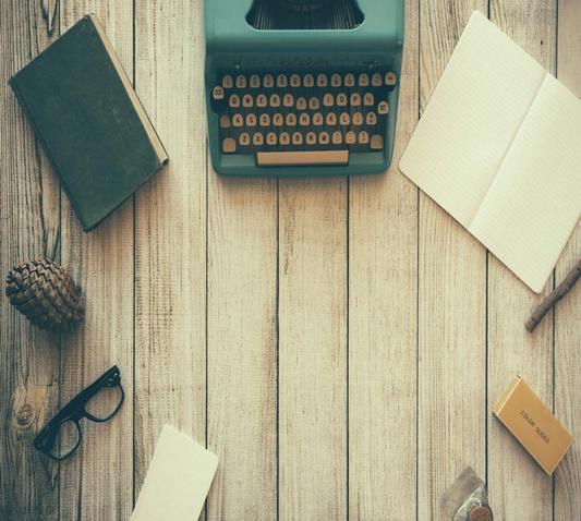 Typemachine, boek en bril op een houten tafel