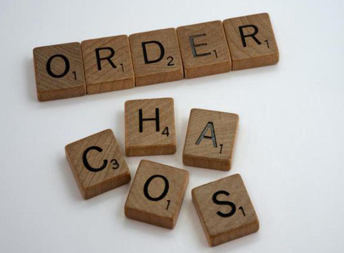 Scrabble-letters die ORDER vormen, met de letters van CHAOS door elkaar